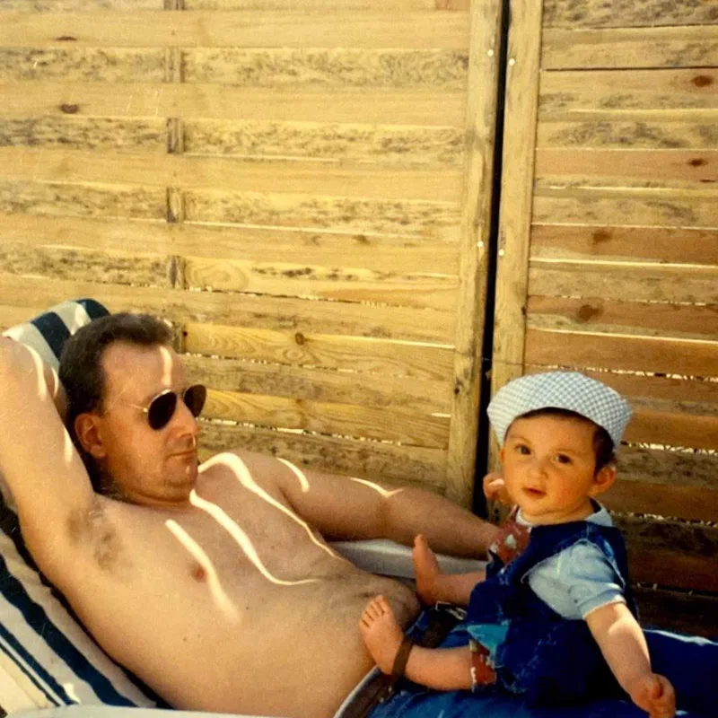 Clément enfant, avec son papa, sur une chaise longue